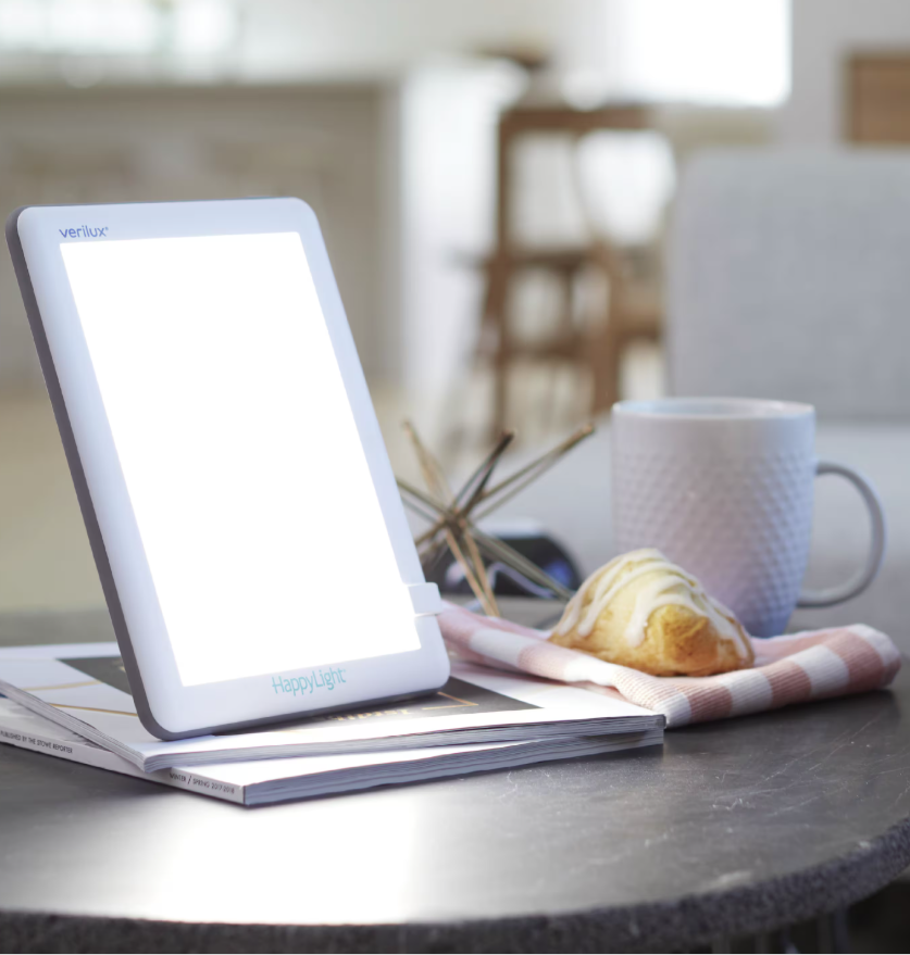 light therapy lamp sitting on magazine with a coffee and pastry close by