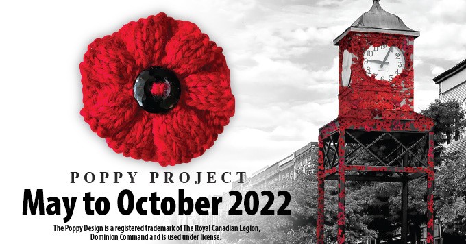 red knitted poppy and red poppies in clock tower